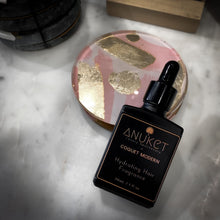 Load image into Gallery viewer, Hydrating hair fragrance bottle resting on a pastel colour acrylic dish displayed on a white marble background