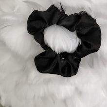 Charger l'image dans la galerie, Black satin Scrunchie displayed on a feather background
