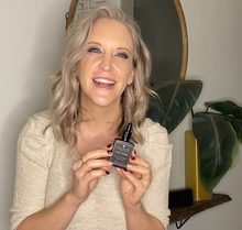 Load image into Gallery viewer, Anuket’s owner smiling holding the hydrating hair fragrance bottle between her hands