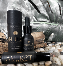 Charger l'image dans la galerie, Pure Sakkara roll on fragrance bottle, box and pure Sakkara diffusing oil bottle displayed on a wood log, leaf and stone background