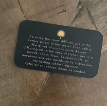 Charger l'image dans la galerie, Small black card with Anuket gold logo with product info writing on a wooden background