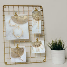 Charger l&#39;image dans la galerie, Gold grid picture holder displaying four pictures including one showing the Sceptre Necklace-Fragrance Diffusing Demi-Fine Jewelry resting on a white background with a flowerpot next to it