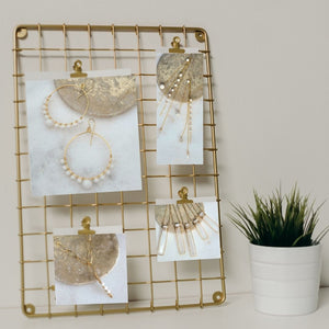 Gold grid picture holder displaying four pictures including one showing the Sceptre Necklace-Fragrance Diffusing Demi-Fine Jewelry resting on a white background with a flowerpot next to it