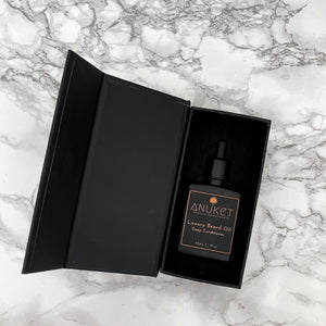 Luxury beard oil deep conditioning bottle laying in a black opened box displayed on a white marble background