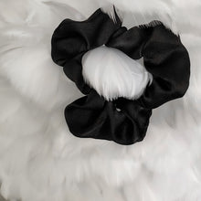 Load image into Gallery viewer, Black satin Scrunchie displayed on a feather background