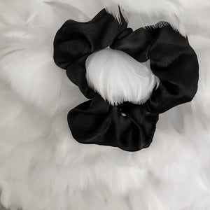 Black satin Scrunchie displayed on a feather background