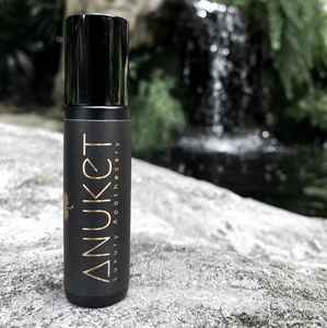 Pure Egyptian Musk Roll-On Fragrance bottle placed on a stone with a waterfall background