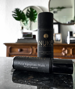 Pure Egyptian Musk Roll-On Fragrance bottle and box on black marble with banana leaves and mirrors in the background