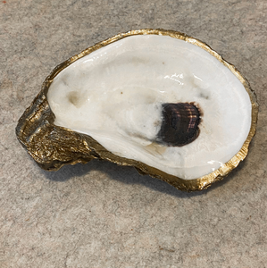 Gold glided oyster dish displayed on a beige marbled background
