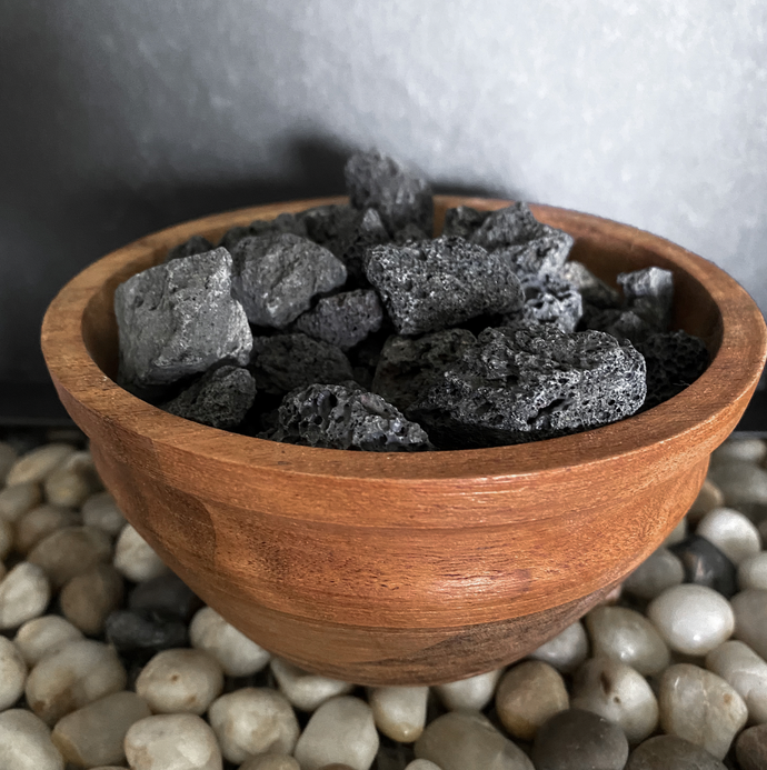 Acacia wood diffusing bowl with black lava stone on a stone background